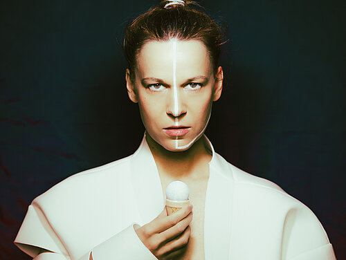  eine Frau in weißem Oberteil, die Haare nach hinten gebunden