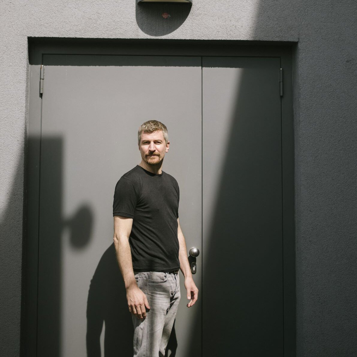Sebastian Eilers steht vor einer Tür und blickt über seine Schulter in die Kqmera.