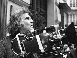 Fernando E Solanas im Halbprofil, vor ihm eine Filmkamera - Schwarz-weiß-Aufnahme von 1985