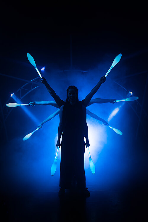 Mensh jongliert mit leuchtenden Kegeln