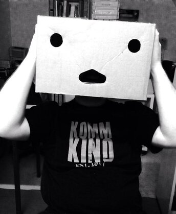 Foto eines Mitgliedes des Kommkinos, der einen Karton mit einem Gesicht über dem Kopf hat