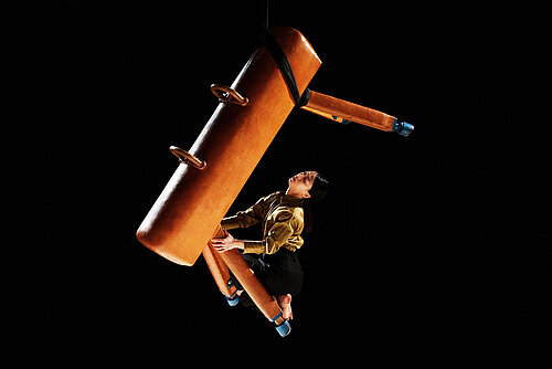 Frau hängt an schwebendem Pauschenpferd