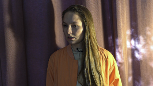 Eine Frau steht vor einem Vorhang und schaut entsetzt 