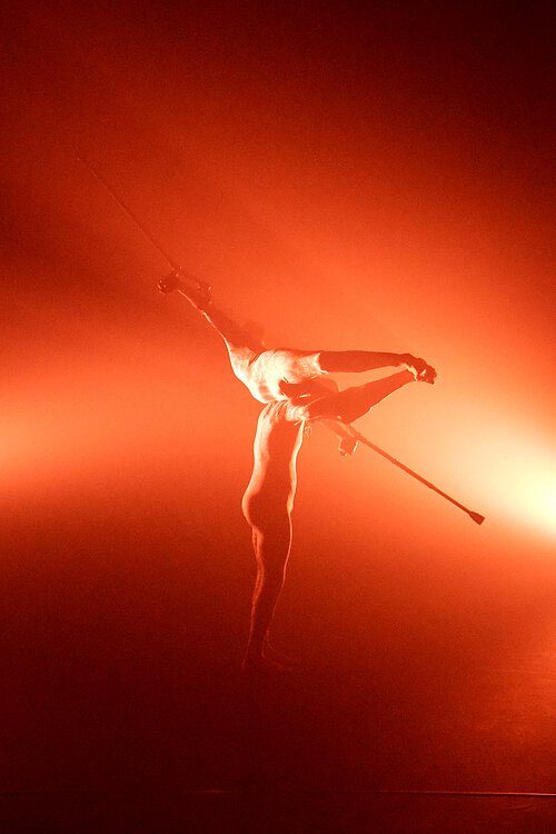 Ein Mann wird in einem dunklen Raum von einem gelben Licht beleuchtet 