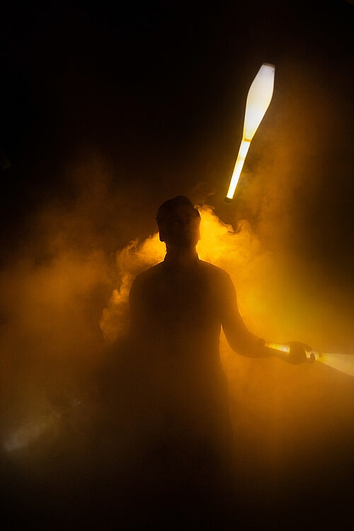 Mensch jongliert mit leuchtenden Kegeln