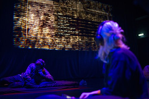 Frau mit Kopfhörern schaut auf projizierte Bildfläche