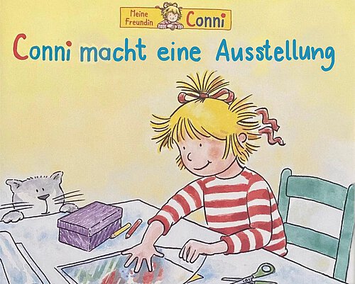 Ein Mädchen sitzt an einem Tisch und zeichnet ein Bild