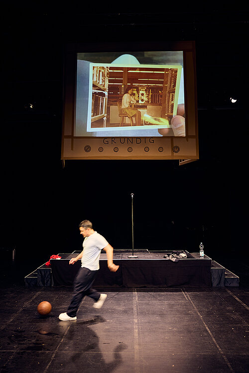 Ein Mann spielt auf der Bühne Fußball
