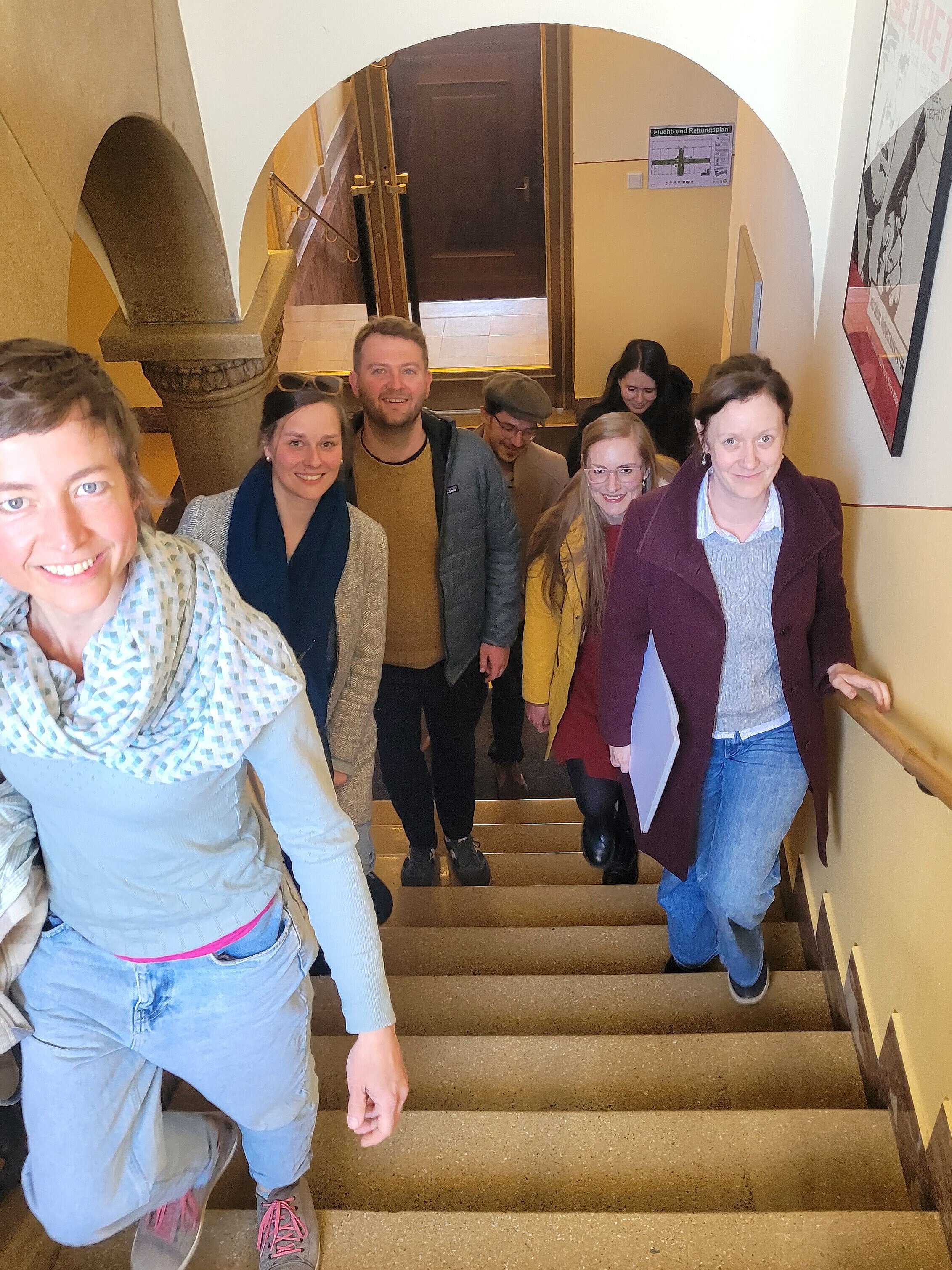 Menschen auf einer Treppe, treppauf zum Fotografen blickend, lächelnd
