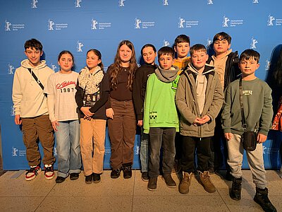 Eine Gruppe von Kindern vor der roten Werbewand des Filmfestvals Berlinale