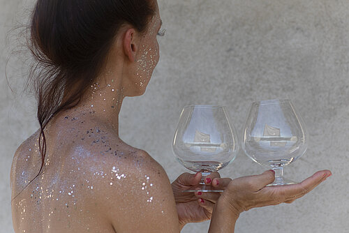 nackter Frauenrücken, sie hält per Hand ein Weinglas auf der Handinnenfläche