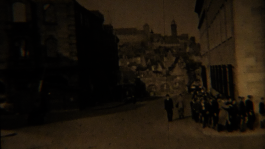 Szenenbild aus einem Archivfilm, zu sehen ist eine Gruppe Männer auf dem Weg zur Berufsberatung