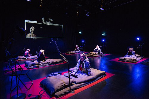 Installation mit Matrazen und IPads an denen Menschen mit Kopfhörern sitzen