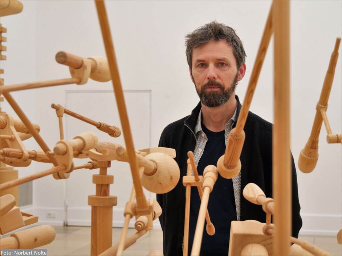 Oliver van den Berg vor seiner Installation Mikros, die in Holz nachgebaute Mikrofone zeigt