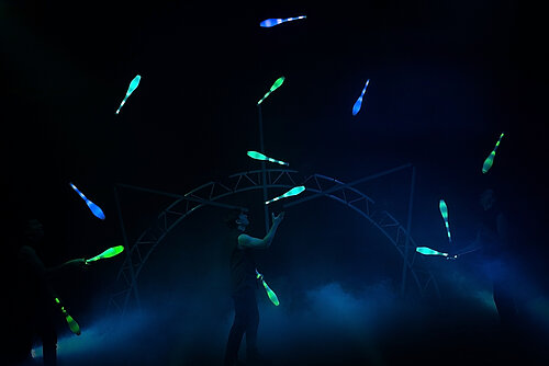 Menschen jonglieren mit leuchtenden Kegeln