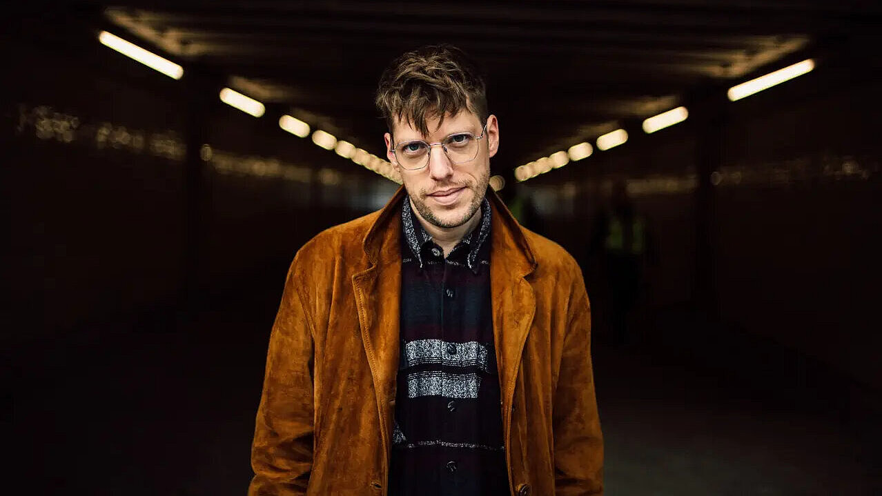 Mensch in orangefarbener Jacke steht in einem Tunnel