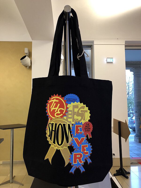 Schwarze Falttasche mit dem Aufdruck des Plakatmotivs zur Ausstellung The Best Show Ever