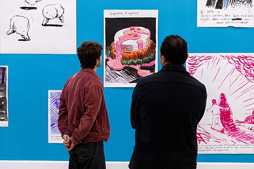 Eine Wand, türkis gestrichen mit bunten, karikaturhaften Zeichnungen von Jan Bräumer