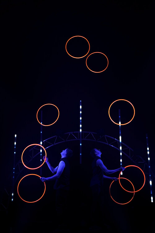 zwei Menschen jonglieren mit leuchtenden Ringen
