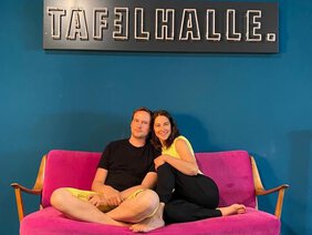 Mann und Frau sitzen zusammen auf rosa Sofa