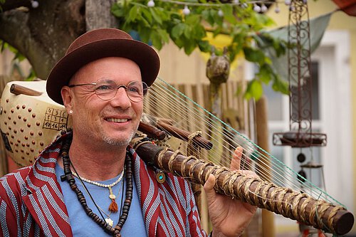 Mann mit Hut und Kora-Instrument über der Schulter