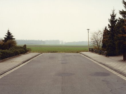 Aufnahme einer leeren Straße die vor einem Feld endet.