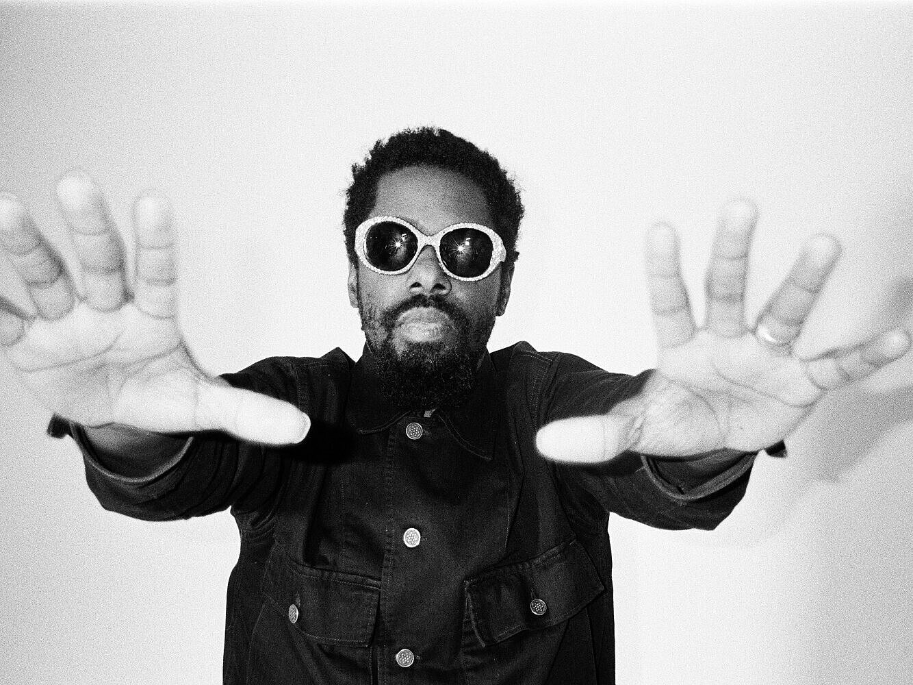 Person mit lockigem Haar und dunkler Jacke streckt beide Hände nach vorne