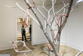 Ein Baum, über und über mit Steinschleudern behängt in der Ausstellung von Oliver van den Berg