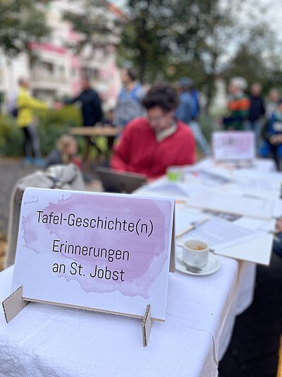 Auf einem Tisch steht ein Aufsteller mit der Aufschrift "Tafel-Geschichte(n), Erinnerungen an St. Jobst"