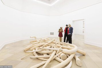 Blick in die Ausstellung von Oliver van den Berg, zu sehen ist eine Ansammlung von in Holz nachgebauten Elefantenstoßzähnen