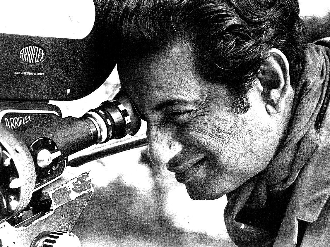 Der Regisseur Satyajit Ray blickt durch den Sucher einer Filmkamera