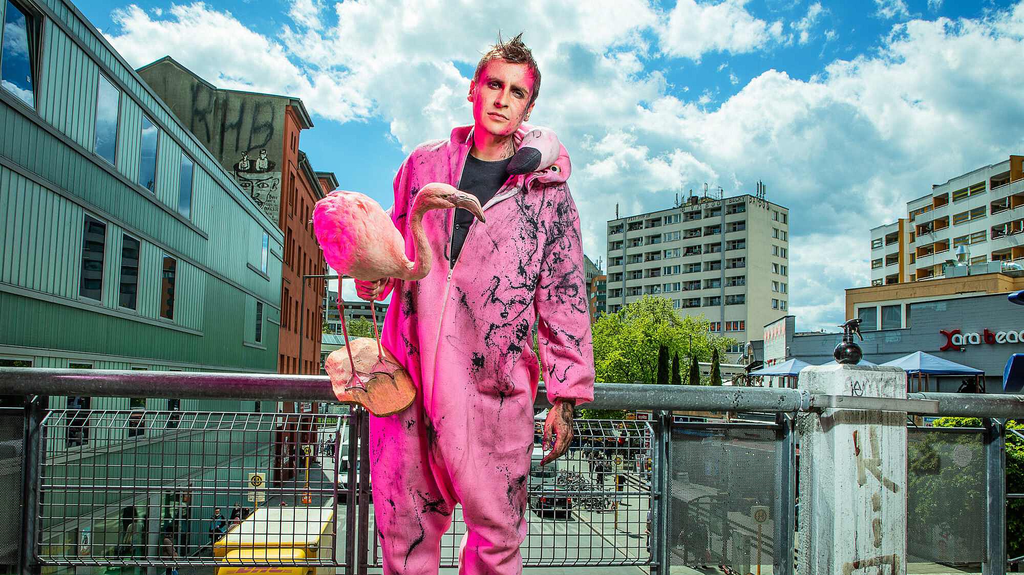 Till Reiners in pinkem Overall mit Plastik-Flamingo