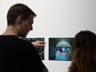 Ein Mann und eine Frau betrachten Fotografien in einer Kunstausstellung
