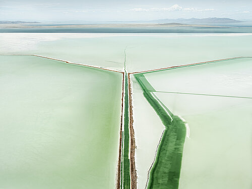 Luftaufnahme eines geraden Kanals, der von grünen Uferstreifen umgeben ist und sich in der Ferne verzweigt.