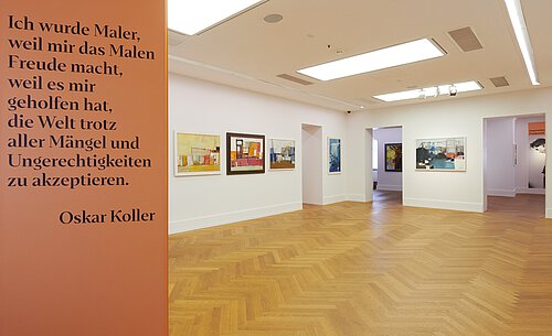 Ausstellungssaal mit Holzparkett und weißen Wänden, an denen farbige Gemälde von Oskar Koller hängen; links an der Wand Zitat von Oskar Koller in schwarzer Schrift auf orangefarbenem Hintergrund.