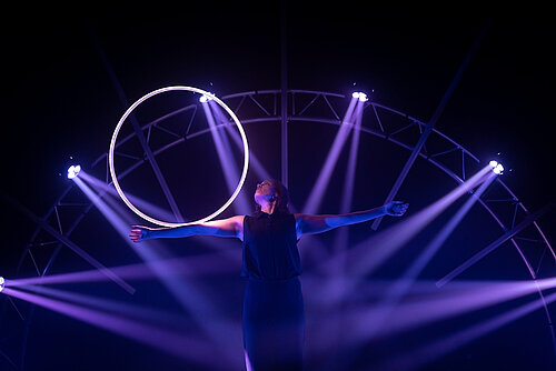 Frau balanciert leuchtenden Ring auf ihrem ausgestreckten Arm