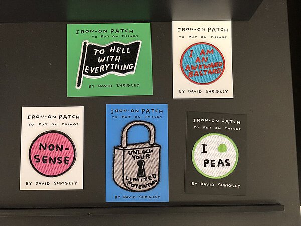 Patches zum Aufbügeln von David Shrigley mit Sprüchen wie zum Beispiel To Hell with Everything oder Unlock your Limided Potential
