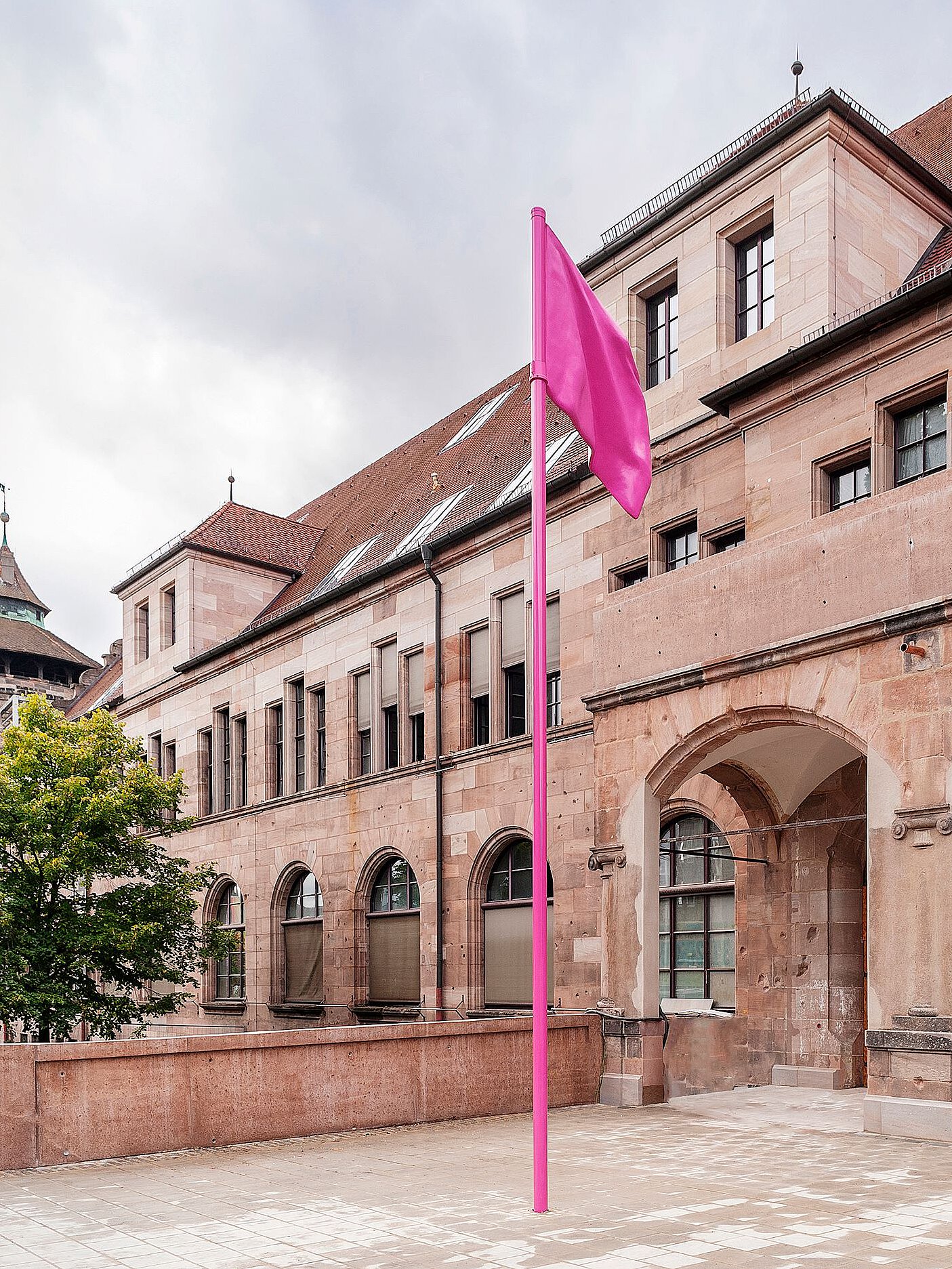 Historisches Gebäude mit Arkadengang und pinker Fahne auf dem Vorplatz