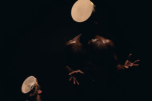 zwei Menschen mit Trommel vorm Gesicht