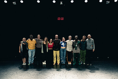 elf Tänzer Arm in Arm auf der Bühne