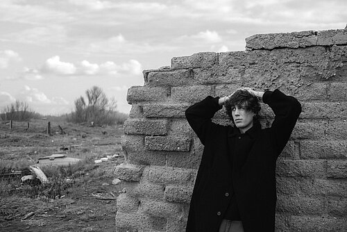 Ein junger Mann steht angelehnt an einer Mauer