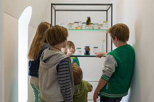 Fünf Kinder betrachten eine Installation in einem kleinen Ausstellungsraum im Dachgeschoss der Kunstvilla.