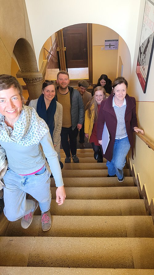 Loci Kollektiv und Mitarbeitende aus Tafelhalle und Museum Industriekultur im ehemaligien Verwaltungsgebäude auf einer Treppe positioniert