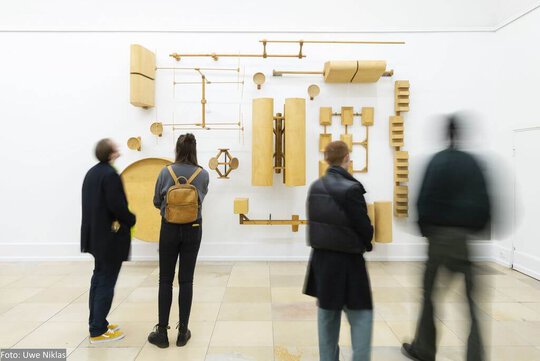 Eine Wandinstallation aus hölzernen Nachbauten von Antennen und Transmitterverschalungen in der Ausstellung von Oliver van den Berg
