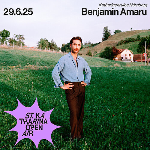 Ein Mann steht auf einer Wiese, im Hintergrund ein Hügel und Häuser + Konzerttermin 29.06.