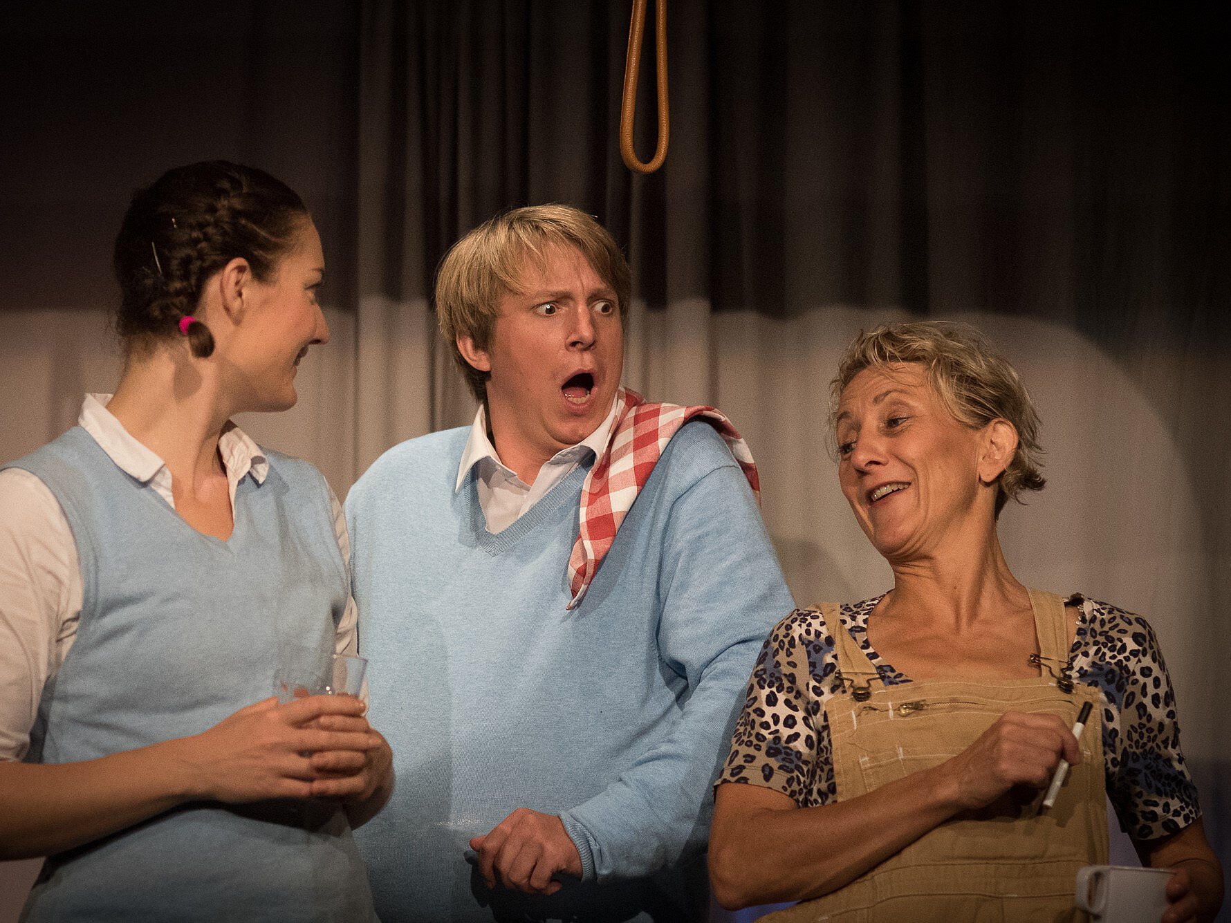 Zwei Schauspielerinnen und ein Schauspieler. Die Schauspielerin ganz links lacht vergnügt, ihr Kollege neben ihr schaut empört