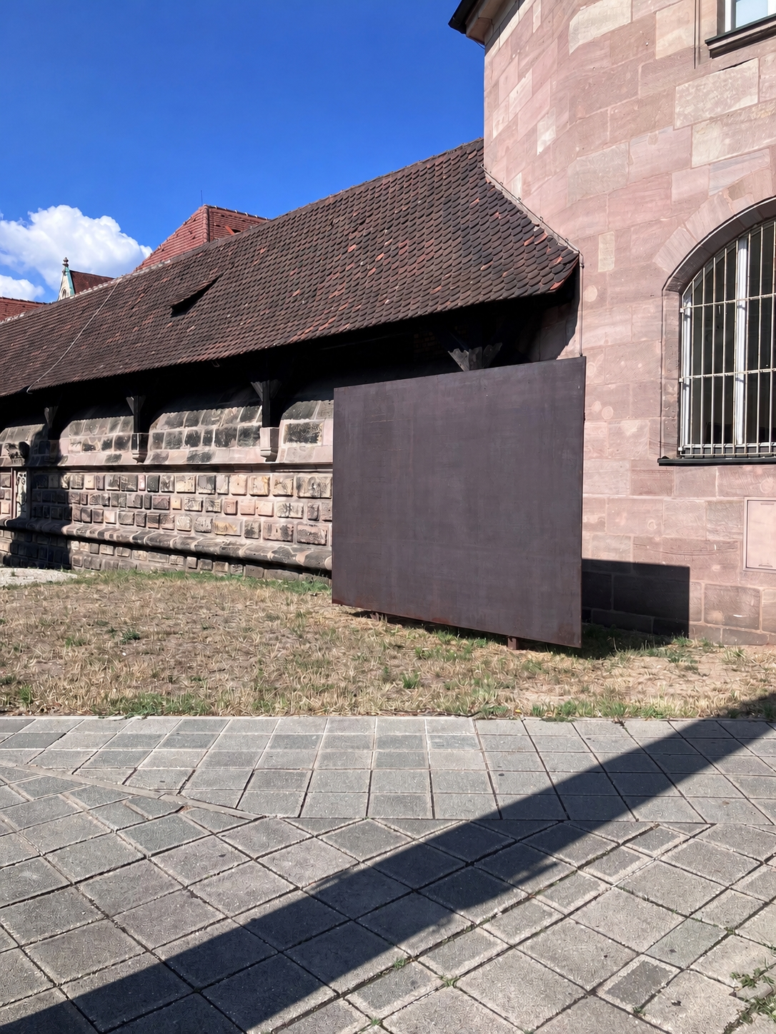 Stahlwand vor historischem Sandsteingebäude