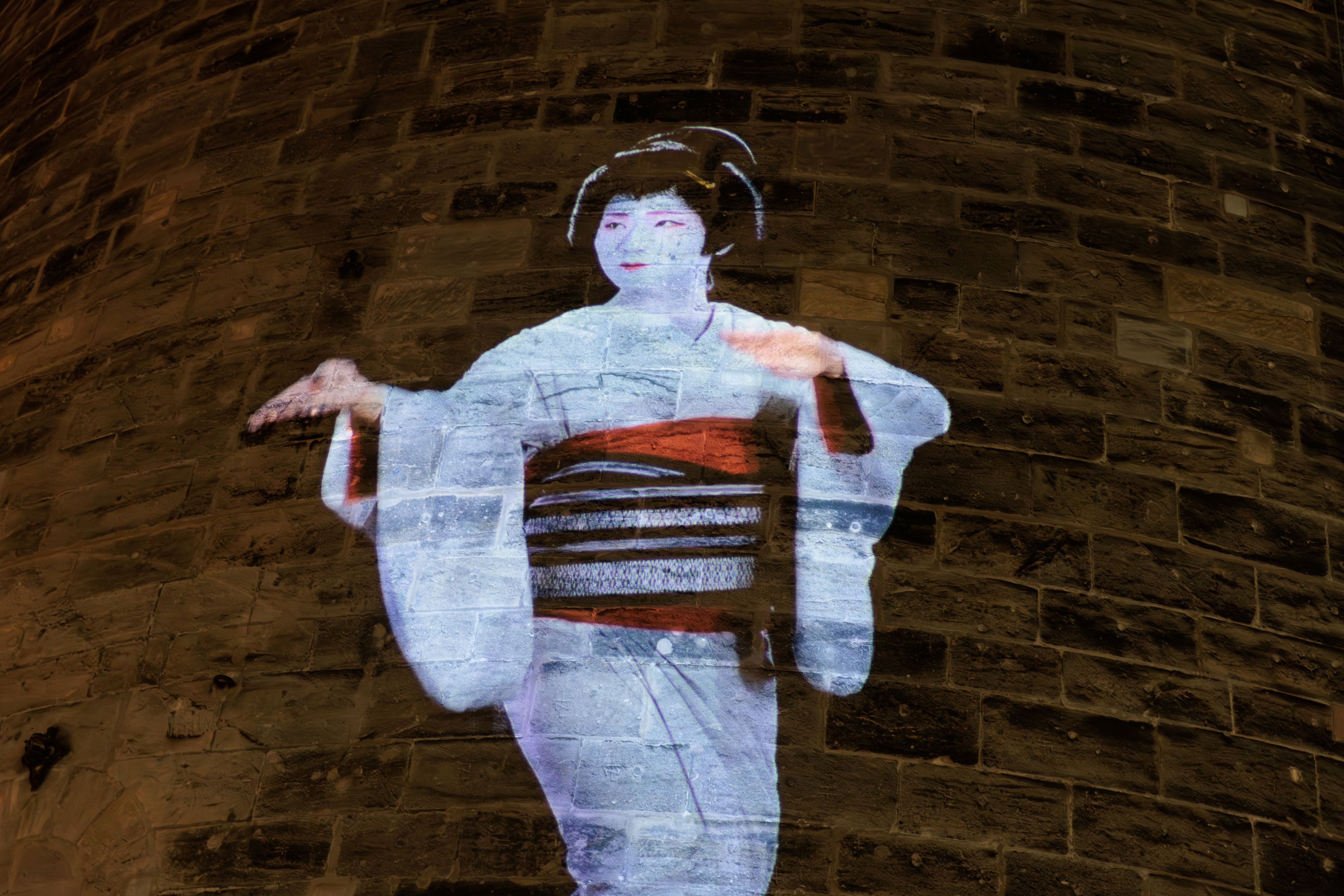 HD-Projektion einer sitzenden Geisha mit traditionellem Kimono auf den runden Backsteinturm Frauentorturm in Nürnberg