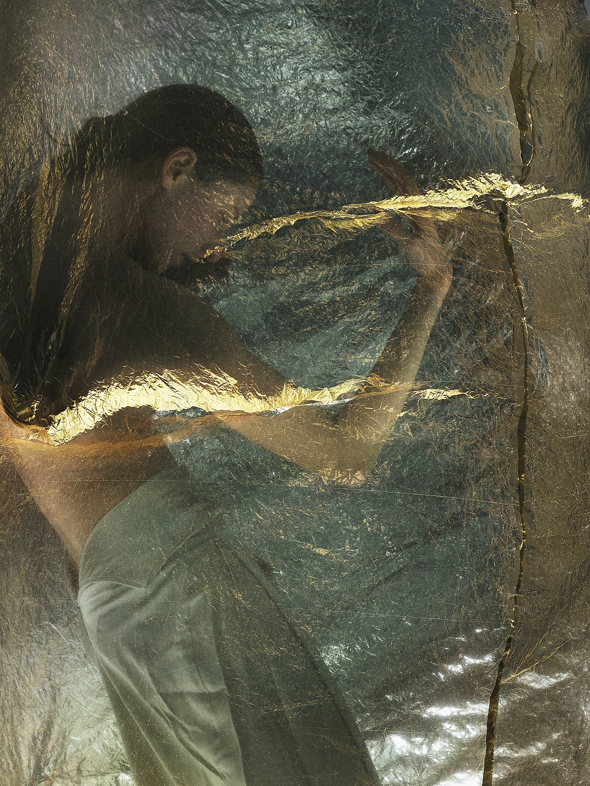 Eine Person hinter einer golden schimmernden , transparentem Stoff