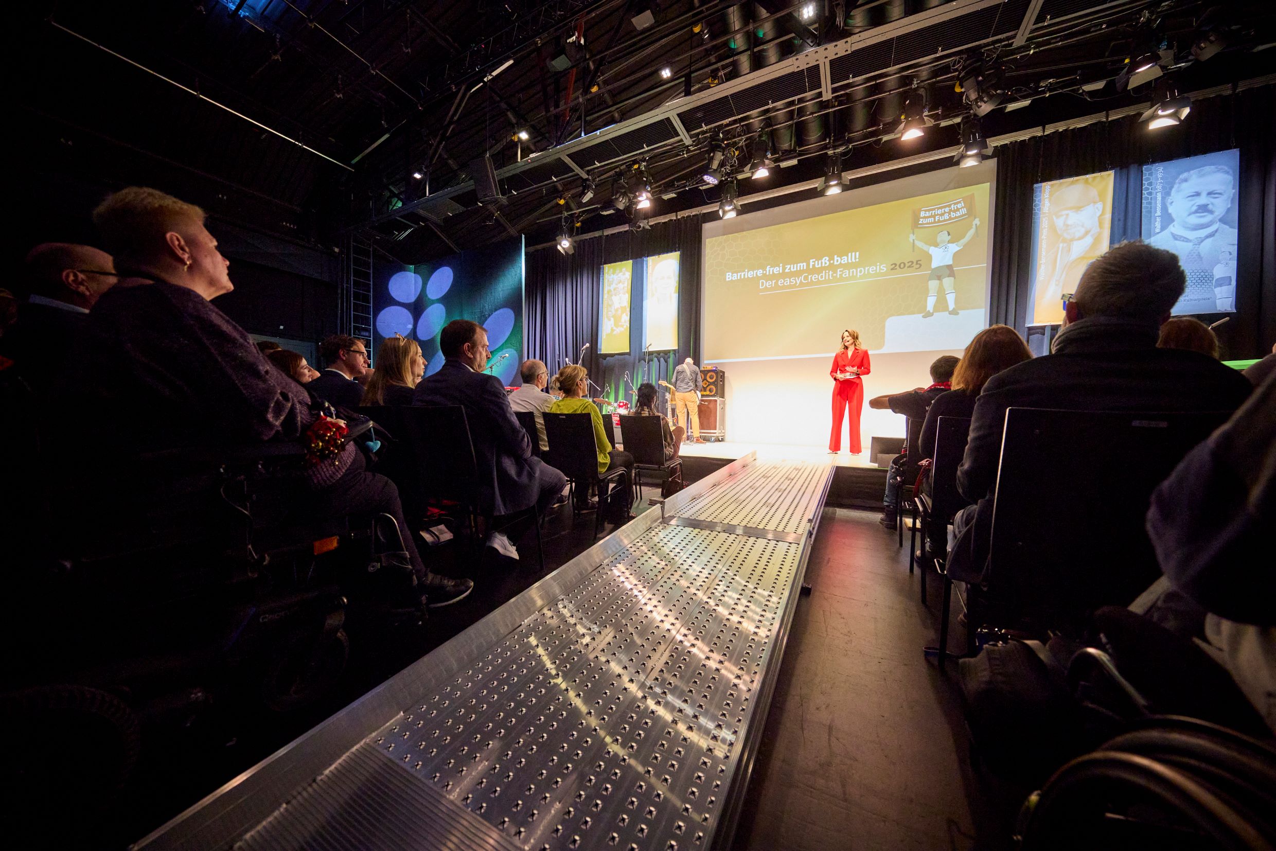 Foto von Katrin Müller-Hohenstein auf der Bühne beim Fußballkulturpreis 2025, im Vordergrund eine silberne Rampe, die zur Bühne führt